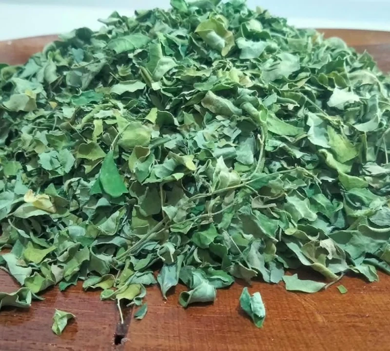 Daun kelor kering pilihan di atas piring kayu