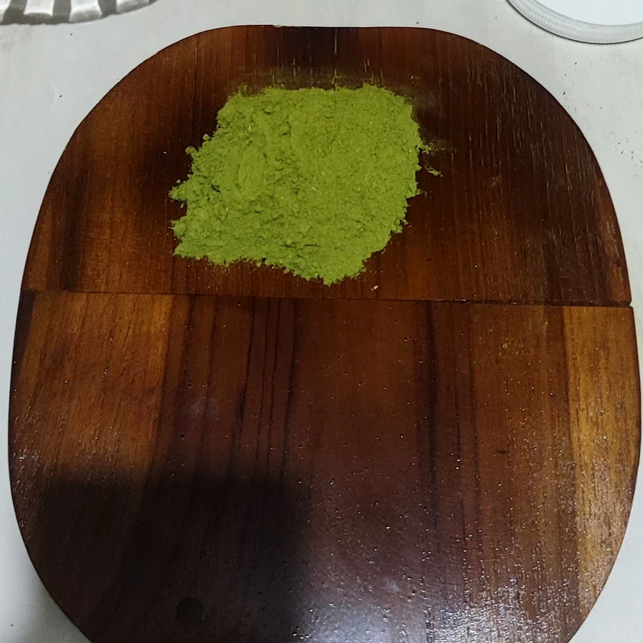 Fine vibrant green moringa powder on teak board