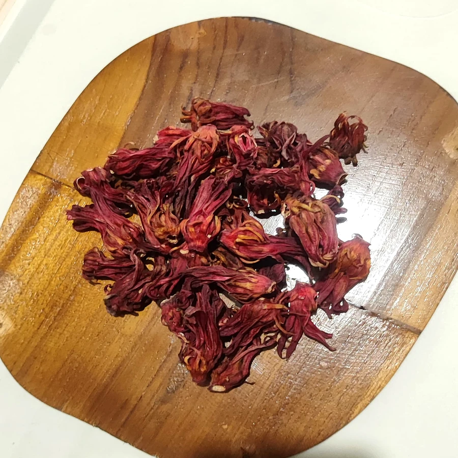 Whole dried red roselle calyces on teak board